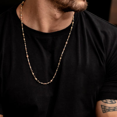 Este exclusivo collar está confeccionado en oro laminado de 18K, con una bola de 5 mm acompañada por neopreno con aros de oro laminado y pinos de acero plateado, fabricado por artesanos con destreza en la técnica del ensamblaje.