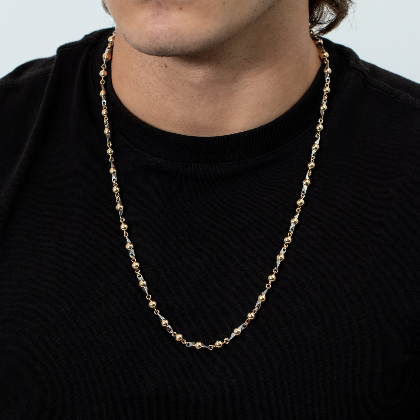 Esta elegante pieza, hecha a mano por expertos artesanos, es un collar de oro laminado de 18K con bolas laminadas doradas de 6mm y 65 cm de largo complementado con pinos de acero 316L con técnica de alambrismo.