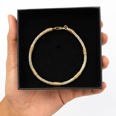 Pulsera artesanal elaborada con lámina de oro laminado 18k, moldeada en una forma cilíndrica de 1 cm de grosor para crear un lujoso aro dorado, adornada con piezas de entorches dorados