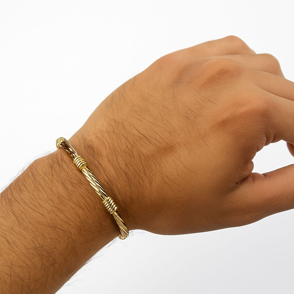 Pulsera artesanal elaborada con lámina de oro laminado 18k, moldeada en una forma cilíndrica de 1 cm de grosor para crear un lujoso aro dorado, adornada con piezas de entorches dorados