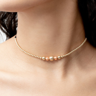 Gargantilla en oro laminado 18k tejida en hilo sintético, con B8MM dorado diamantado, B6MM rosado diamantado y plateada y B3MM dorada, elaborada por expertos artesanos en el tejido macramé.